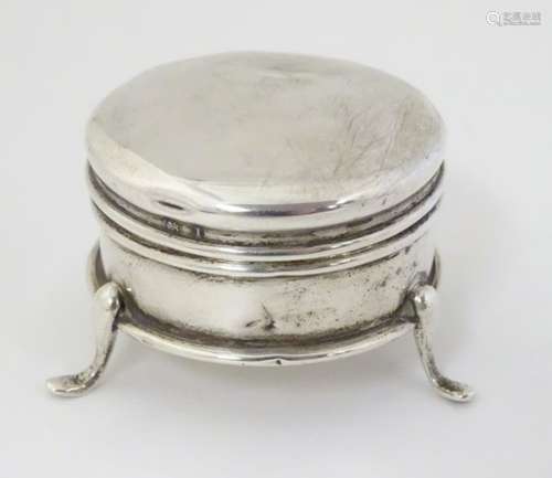 A small silver ring box of circular form on three outswept feet.