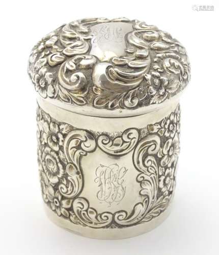 A silver pot of cylindrical form with domed lid and embossed decoration hallmarked Chester 1902