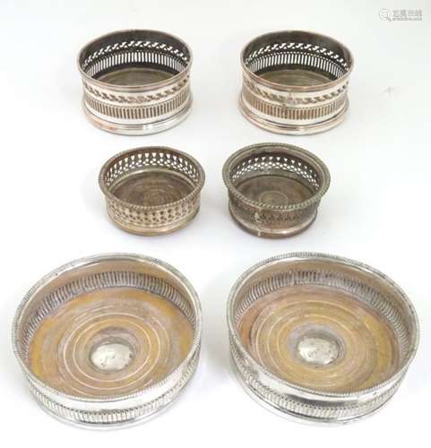 6 assorted silver plate bottle coasters with turned wooden bases.