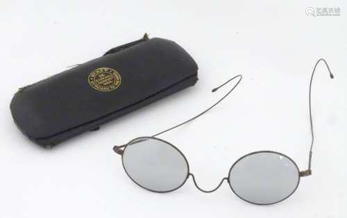 A cased pair of Edwardian spectacles / glasses with a steel frame,