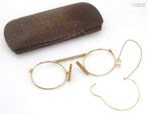 A cased pair of Edwardian pince nez spectacles / glasses with a yellow metal frame,