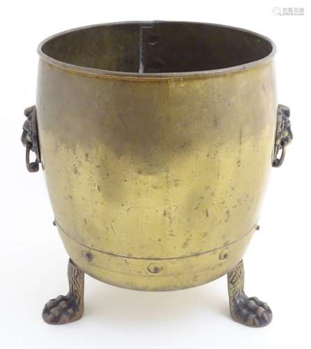 An early-mid 20thC brass coal bucket, with lion's paw handles and standing on three lion's paw feet.