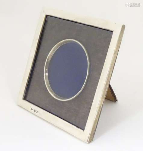 A silver photograph frame of squared form with central circular aperture The whole 6 1/2