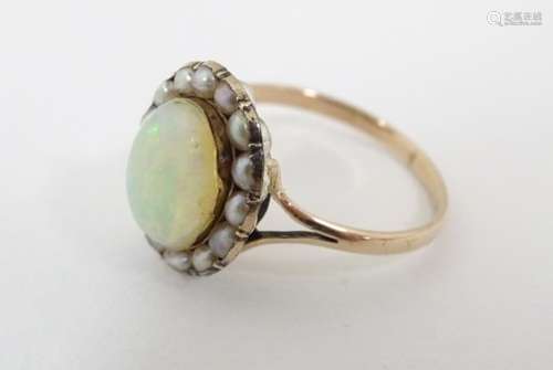 A 8ct gold ring set with central opal bordered by seed pearls.