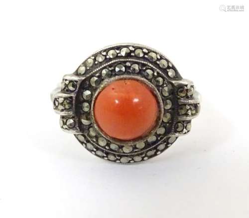 A silver ring set with central coral cabochon bordered by marcasites in an Art Deco setting.