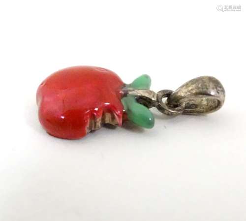 A silver pendant / charm formed as a bitten apple with enamel decoration.