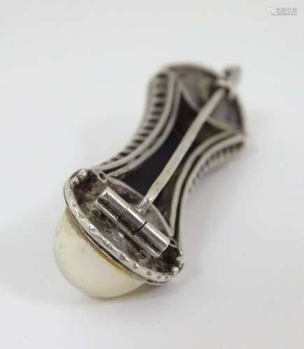 A white metal brooch set with onyx and pearls in an Art Deco setting.