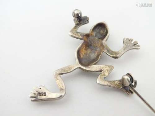 A silver brooch formed as a frog decorated with marcasites and having red stone eyes. 1 ½” long.