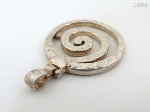 A silver pendant of spiral form with hammered decoration.