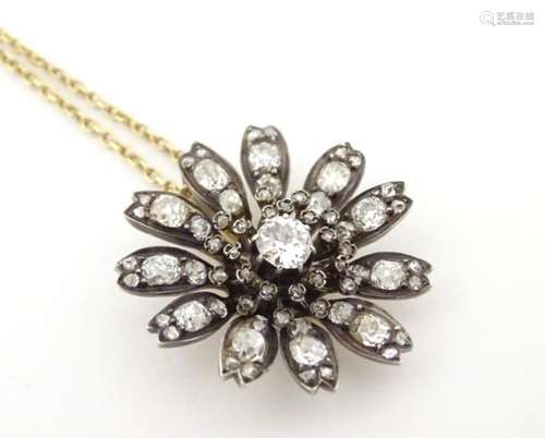 A 9ct gold chain set with a gold and diamond pendant of flower form. The central diamond approx 0.