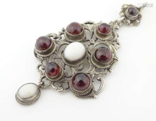 A Continental silver and white metal pendant set with opal and garnet cabochon.