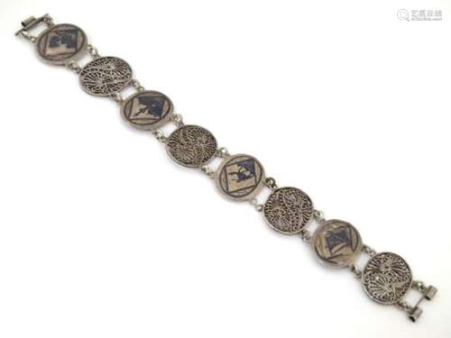 A silver bracelet with niello decorated oval and filigree links.