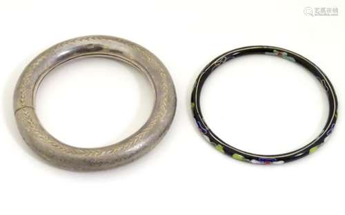 A silver bangle bracelet together with another with black lacquer and enamel detail.