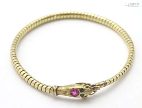 An 18ct gold bracelet formed as a snake / serpent set with ruby spinel to head and green paste eyes.