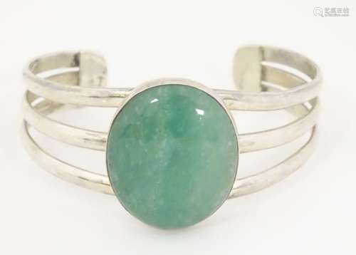 A silver bangle bracelet set with large aventurine cabochon to centre.