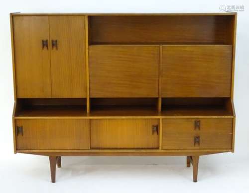 Vintage Retro: A teak sideboard with an open shelf above two fall front cupboards,