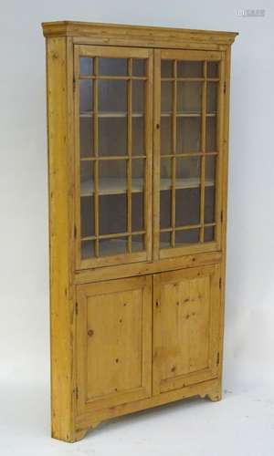 A 19thC large pine corner cupboard with a moulded cornice above two astragal glazed doors and two