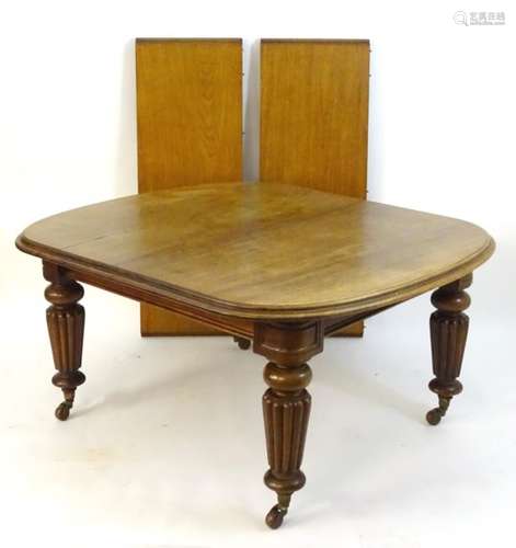 A mid 19thC mahogany dining table with moulded rounded edges and standing on large reeded tapering