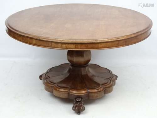 An early Victorian mahogany circular tilt top pedestal breakfast table having lions paw feet and a