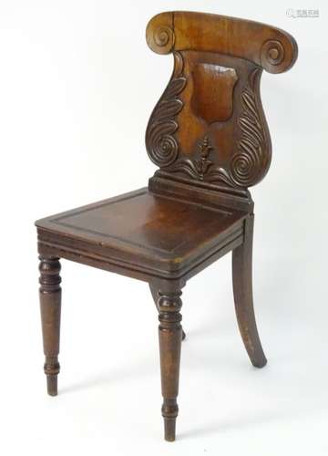 A mid 19thC mahogany hall chair with a lyre shaped back, scrolled ears and foliate carving,