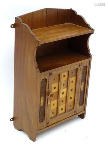 A mid 20thC walnut wall cabinet / table cabinet with a sample wood door and inlaid decoration.