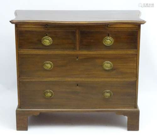 An early 19thC mahogany serpentine fronted chest of drawers comprising 2 short over 2 long drawers,