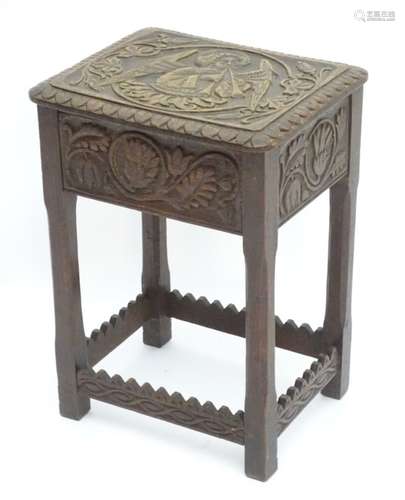 An early 20thC oak stool, the top with relief carving of an archangel playing two pipes,