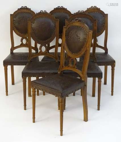 A set of six oak Louis XVI style dining chairs with carved cresting rails and embossed leather back