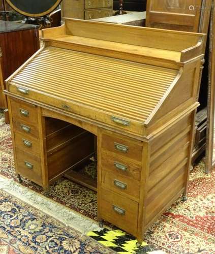 An early / mid 20thC tambour fronted desk with a moulded upstand above a sliding tambor front,