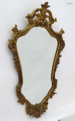 A mid / late 20thC gilt wood mirror with a carved floral frame. 19