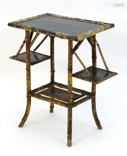 An early / mid 20thC folding bamboo table with a black lacquered top and two painted under tiers,