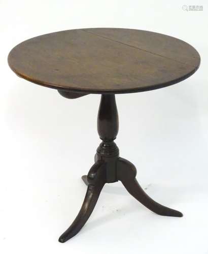 An early 19thC oak topped tripod table with a circular tilt top above a turned stem with three