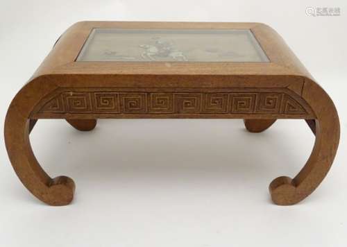 A mid / late 20thC Singaporean low table with a glass top and applied decoration depicting a man on