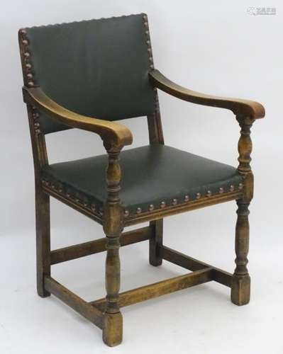 A 20thC oak open armchair with green upholstery and stud detailing.