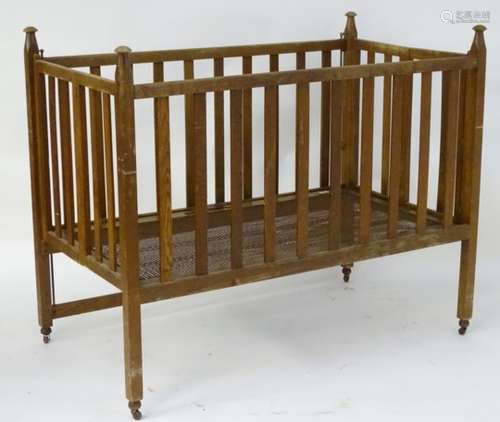 An early 20thC baby crib of slatted construction with a fall front,