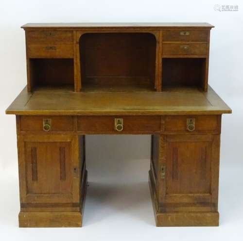 An early 20thC Arts & Crafts oak desk with a raised back gallery containing four short drawers