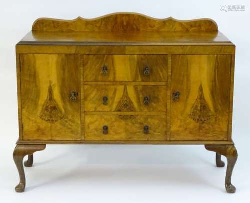 A mid 20thC walnut sideboard with a shaped up stand above three short drawers flanked by two