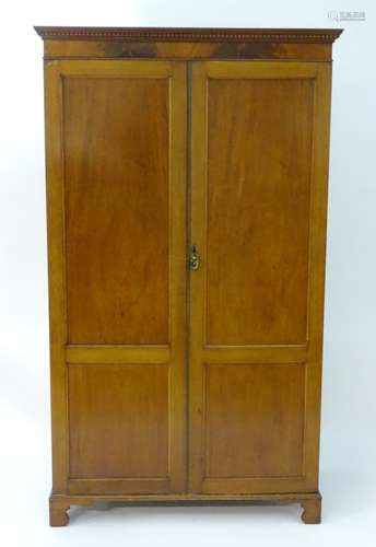 An early 20thC mahogany wardrobe with a small dentil moulded cornice and flame mahogany frieze