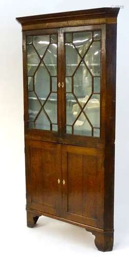 A mid / late 18thC oak corner cupboard with a moulded cornice above two astragal glazed doors