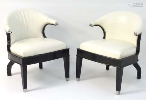 A pair of Art Deco armchairs with white leather upholstery and ebonised wooden frames.