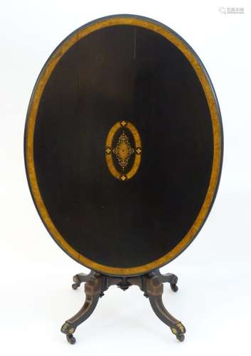 A Victorian ebonised and burr walnut table with a gilt brass edged table top above four fluted