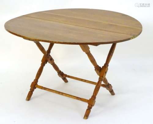 A late 19thC pine topped coaching table with a folding base and four turned legs united by turned