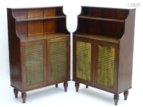 A pair of mahogany Regency bookcases with waterfall shaped shelves above grilled doors and standing