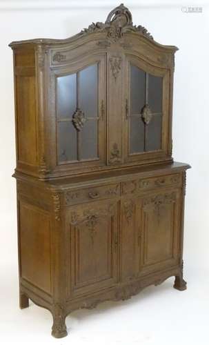 A late 19thC / early 20thC carved oak French buffet with a heavily carved pediment above two glazed