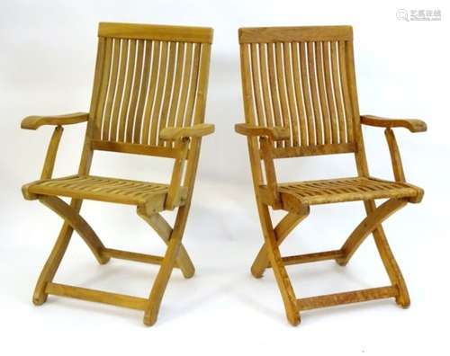 A pair of teak folding steamer chairs with slatted backrests and seats, bearing plaque ‘tecknique,