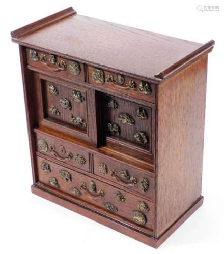 A Japanese shodhana table cabinet, with drawers and sliding panels, decorated with applied