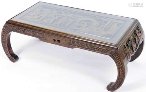 An early 20thC Chinese hardwood low table, heavily carved with figures, interior scenes, etc., on