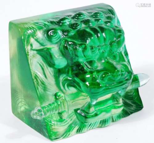 A jade coloured glass sculpture paperweight, of a lion's head with sword to the mouth, possibly
