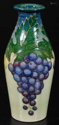 A Dennis China Works grape vase, decorated with green and white grapes and vine leaves on a cream