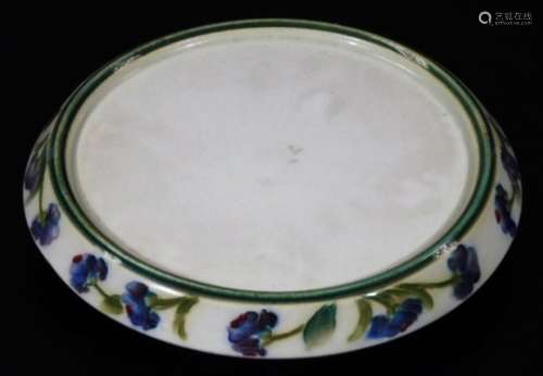 An early 20thC Macintyre pottery teapot stand, decorated with a band of blue flowers, marked in